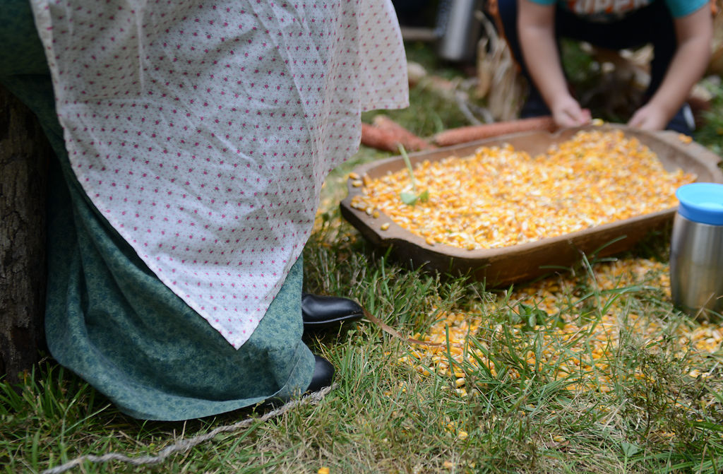 Jenna Peavler sits and grinds corn into flour at the Heritage Festival